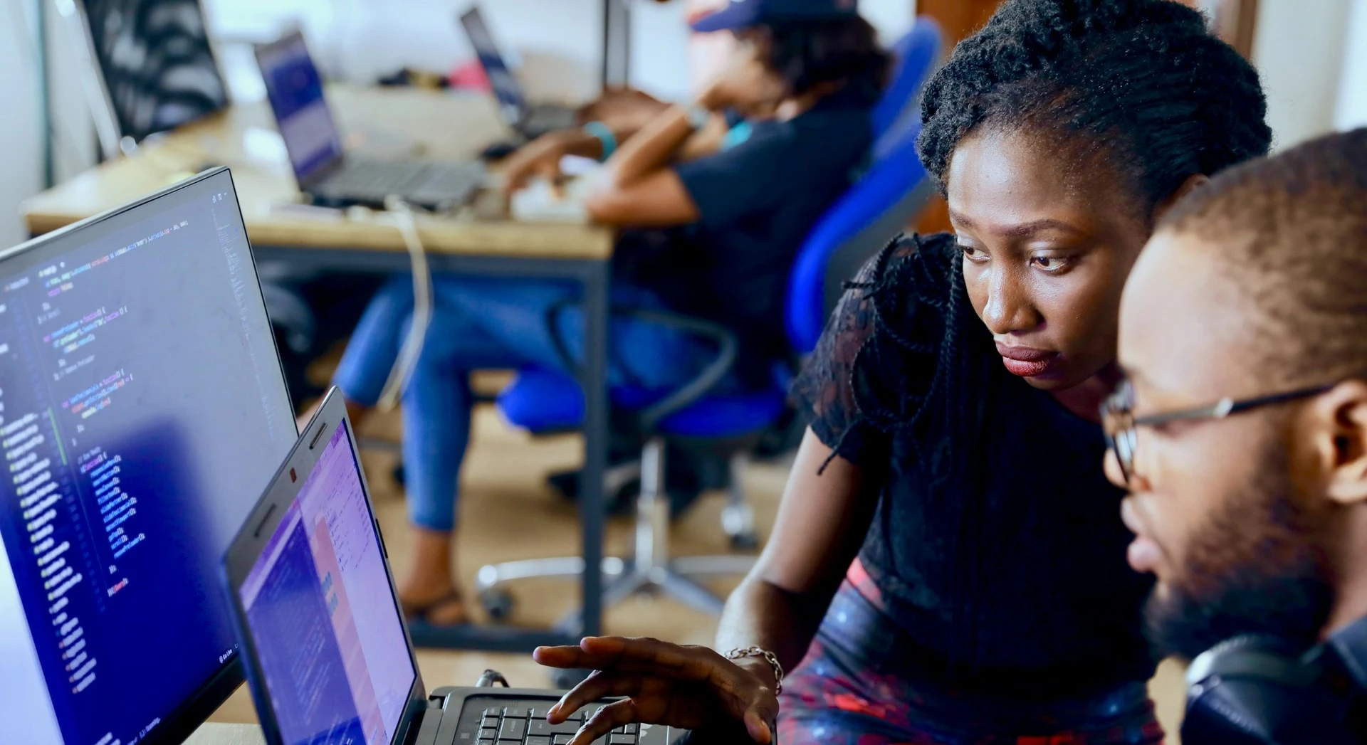 Développeurs collaborant devant un écran de code lors d'une session de travail en équipe.